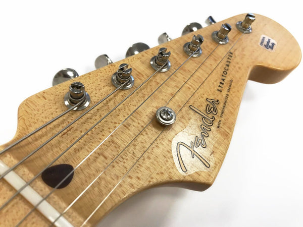Close-up of natural wood Fender Stratocaster guitar headstock with tuning pegs and strings against white background