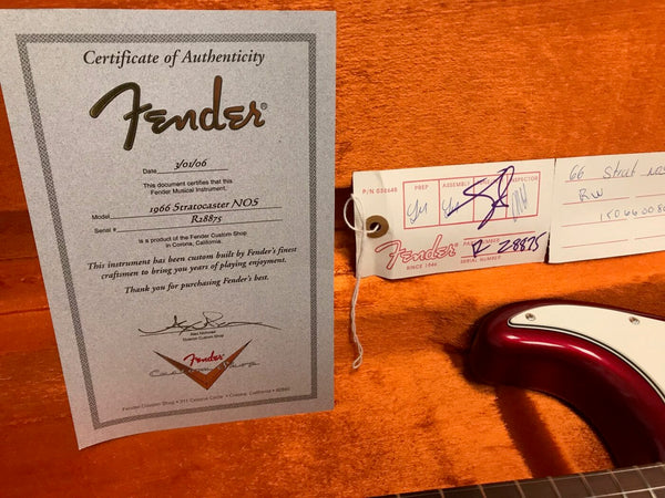 Fender Certificate of Authenticity for 1966 Stratocaster NOS with serial number R28875 and Fender Custom Shop inspection tag in orange guitar case background