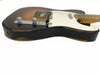 Close-up of vintage-style electric guitar body with worn black and brown finish, chrome control knobs, white pickguard, and maple neck on white background