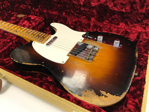 Vintage sunburst electric guitar with wear and relic finish in red velvet-lined tweed case, close-up of body and maple neck.