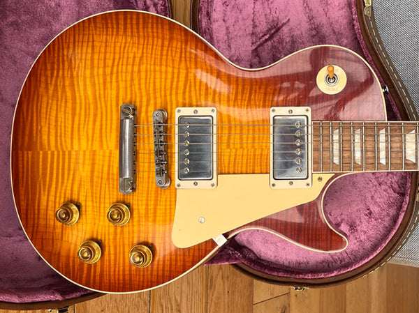 Sunburst finish electric guitar with dual humbucker pickups, cream pickguard, four gold control knobs, and rosewood fretboard, resting in a purple velvet-lined guitar case.