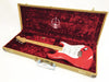Red Fender Stratocaster electric guitar with maple neck in open tweed hard case lined with red plush interior, 60th anniversary edition emblem visible inside case