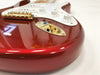 Close-up of red electric guitar body with gold hardware, white control knobs, and input jack on white background