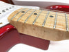 Close-up of electric guitar neck with maple fretboard and silver frets on red guitar body