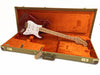 Fender Stratocaster electric guitar in vintage tweed hard case with orange plush interior, featuring cherry red body, white pickguard, and maple neck