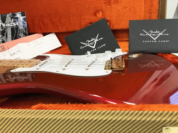 Close-up of red Fender Stratocaster electric guitar inside tweed hard case with Fender Custom Shop documentation and care booklets on orange plush lining