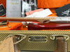 Fender custom guitar case with leather handles and metal nameplate, vintage tweed texture and certificate of authenticity in background, guitar neck and red guitar body visible inside orange plush lining case