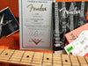 Fender Custom Shop Certificate of Authenticity for 1956 Stratocaster NOS guitar with serial number R56911, displayed with Fender manuals and the guitar fretboard on orange fabric background