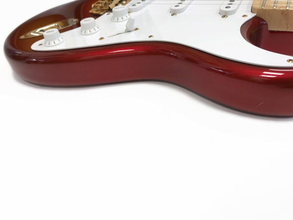 Close-up of red electric guitar body with white pickguard and control knobs on white background