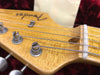 Close-up of Fender electric guitar headstock with tuning pegs and strings on maple neck with vintage finish
