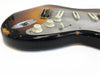 Close-up of worn vintage electric guitar body with sunburst finish, cream tone knobs, and white pickup covers on a white background