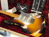 Vintage Fender Custom Shop Stratocaster electric guitar with sunburst finish and worn relic body, displayed in a red plush-lined case with Fender Custom Shop certificate and owner's manual