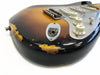 Close-up of sunburst electric guitar body with worn and chipped finish showing relic wear, featuring white tone knobs and output jack socket.