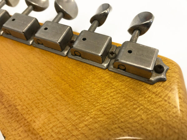 Close-up of vintage Kluson guitar tuning pegs on yellow wood guitar headstock