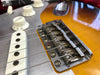 Close-up of electric guitar bridge, strings, white pickup, and volume control knobs on sunburst finish body at Coffee House Guitars product listing