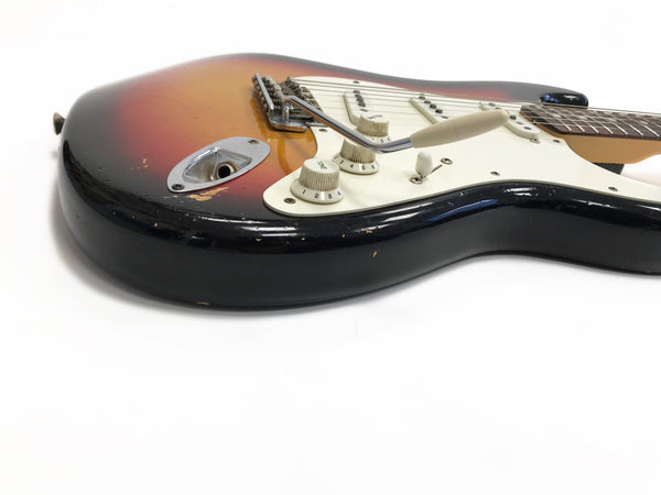 Close-up of a vintage sunburst electric guitar body with white pickguard, tone and volume knobs, and a tremolo arm on a white background