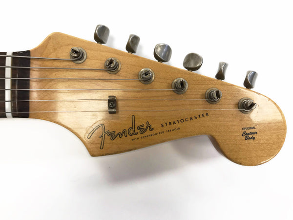 Close-up of vintage Fender Stratocaster electric guitar headstock with tuning pegs and original contour body logo on natural wood finish