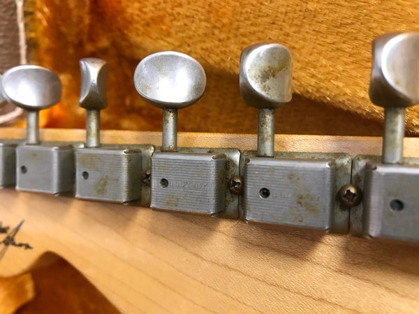 Close-up of vintage metal tuning pegs on wooden guitar headstock showing wear and patina, detailed view of guitar machine heads for string tuning.