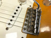 Close-up of vintage Fender electric guitar bridge and white single-coil pickup with six strings and tone control knob
