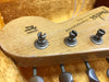 Close-up of Fender Stratocaster guitar headstock with original contour body text and tuning pegs in vintage case lining