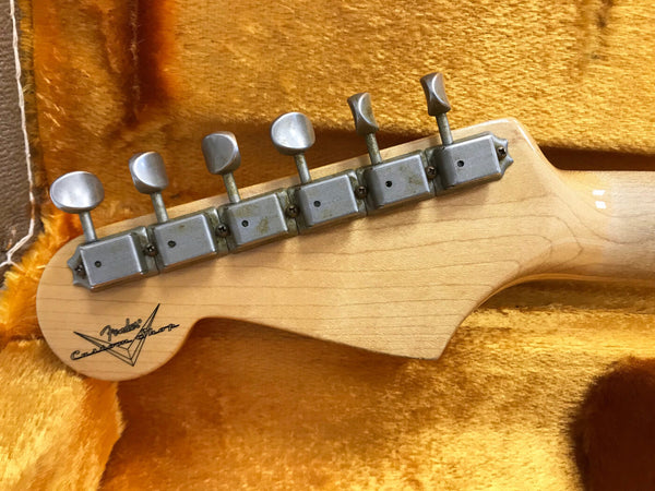 Close-up of Fender Custom Shop electric guitar headstock with vintage tuning pegs on yellow plush case lining
