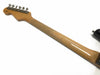 Glossy maple neck and back of headstock with six tuning pegs and a black guitar body edge visible on white background