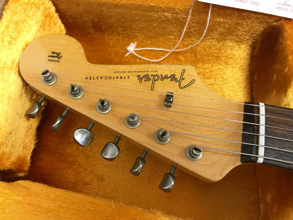 Fender Stratocaster guitar headstock with tuning pegs and original Genuine Fender Decal inside orange plush guitar case