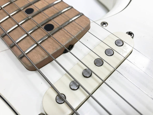 Close-up of white electric guitar pickup and maple fretboard with metal frets and strings