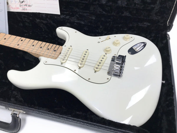 White electric guitar with maple neck and three single-coil pickups in black plush-lined hard case