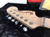 Close-up of Fender Stratocaster maple headstock with tuning pegs and strings on black plush guitar case interior