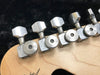 Close-up of Fender guitar tuning pegs with "USA Supreme" engraving on chrome machine heads mounted on light maple guitar headstock.