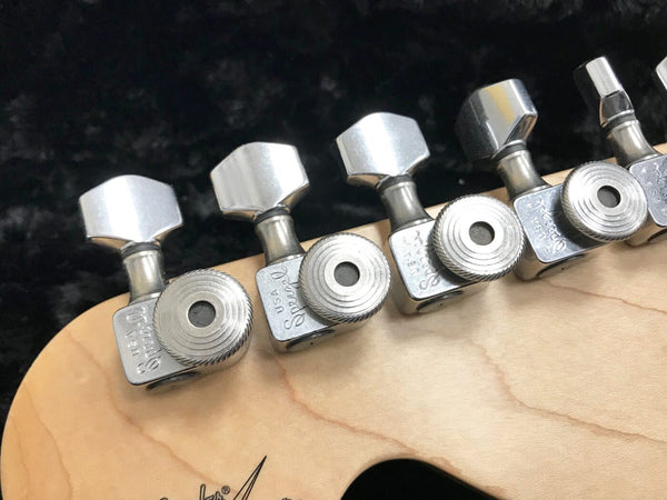 Close-up of Fender guitar tuning pegs with "USA Supreme" engraving on chrome machine heads mounted on light maple guitar headstock.