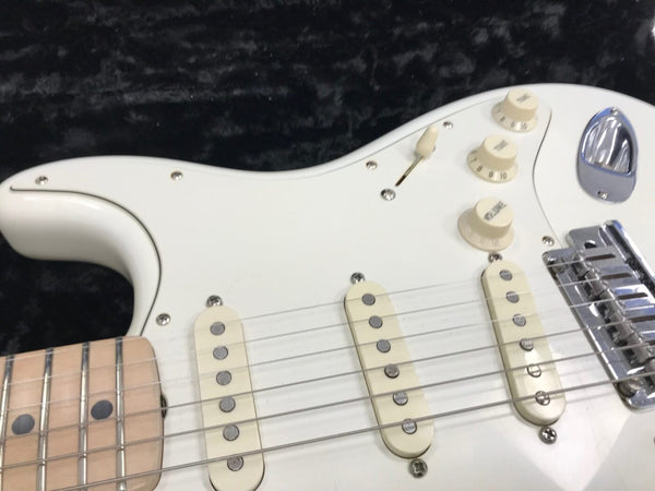 Close-up of white electric guitar body showing pickups, control knobs, and bridge on black background