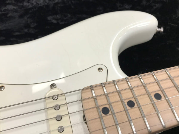 Close-up of white electric guitar body and maple fretboard with metal frets and black dot inlays on black background