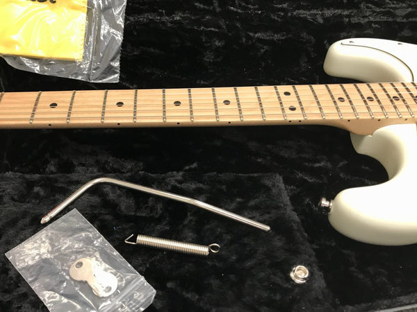 Close-up of white electric guitar neck and body with maple fretboard, showing tremolo arm, spring, and guitar case interior accessories from Coffee House Guitars product listing.