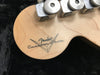 Close-up of Fender Custom Shop logo on natural wood guitar headstock with vintage-style tuning pegs