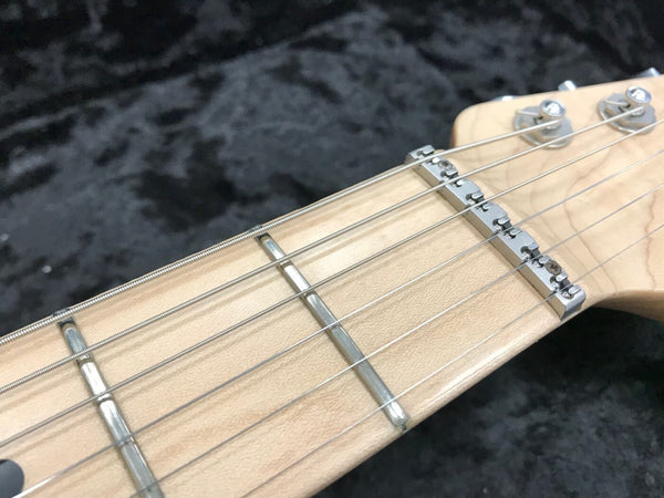 Close-up of maple guitar neck and headstock with metal frets and tuning pegs on black textured background