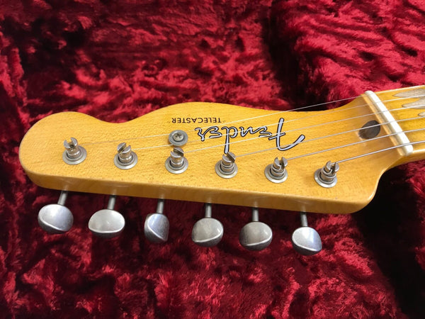 Close-up of Fender Telecaster guitar headstock with tuning pegs on red velvet background