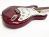 Close-up of red electric guitar body with white pickguard and control knobs on white background