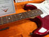 Close-up of red Fender Stratocaster electric guitar neck and body in orange plush case with Fender Custom Shop certificate