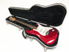 Red electric guitar with white pickguard and rosewood fretboard in black hard case with plush interior, displayed on white background