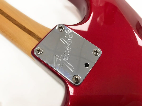 Close-up of Fender guitar neck plate with engraved logo on red electric guitar body and maple neck with skunk stripe