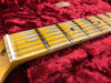 Close-up of vintage guitar neck with maple fretboard and metal frets resting on red plush case lining
