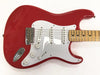 Red electric guitar with white pickguard and maple neck, three single-coil pickups, chrome bridge, and control knobs on a white background.