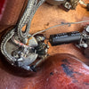 Close-up of vintage guitar wiring showing braided shielding, soldered potentiometer, and black FUJICON capacitor inside guitar cavity