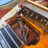 Close-up of vintage electric guitar pickup cavity showing braided pickup wires, metal pickup baseplate, and part of guitar body with rosewood fretboard edge.