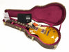 Gibson Les Paul electric guitar in sunburst finish inside open brown hardshell case with pink interior and included warranty and certificate documents