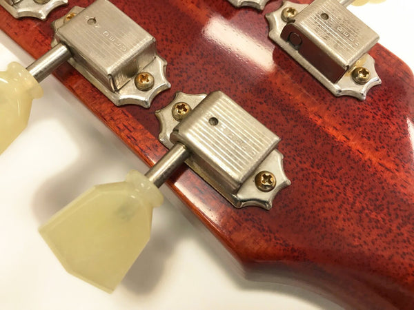 Close-up of vintage guitar tuning pegs with cream plastic tuning keys on mahogany guitar headstock