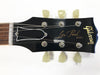 Close-up of Gibson Les Paul Model guitar headstock with tuning pegs and strings on a white background