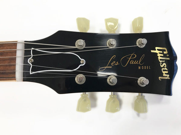 Close-up of Gibson Les Paul Model guitar headstock with tuning pegs and strings on a white background